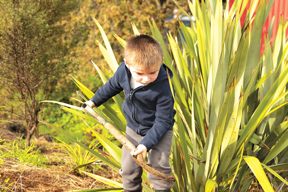 Boy digging near flax. (Photo credit: Dawn Dutton).