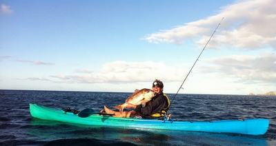 Man holding fish in kayak.