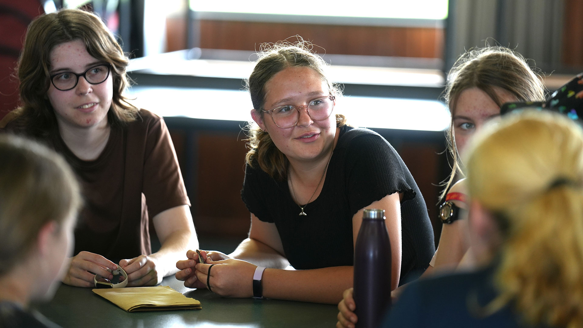 Young women sit around a table talking.