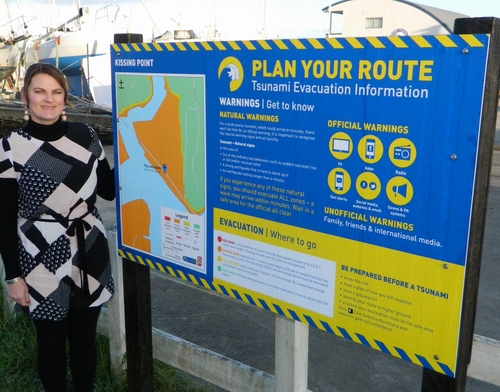 Victoria Harwood stands beside tsunami information board.