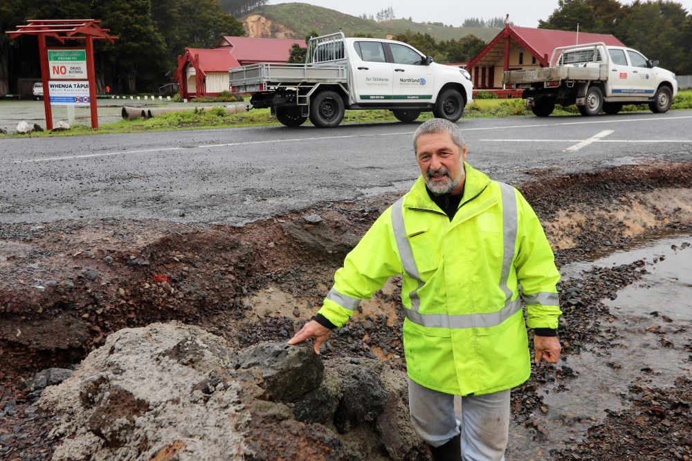 Man standing in rain affected ditch.