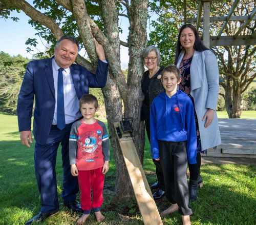Ministers with children and pest trap in front of a tree.