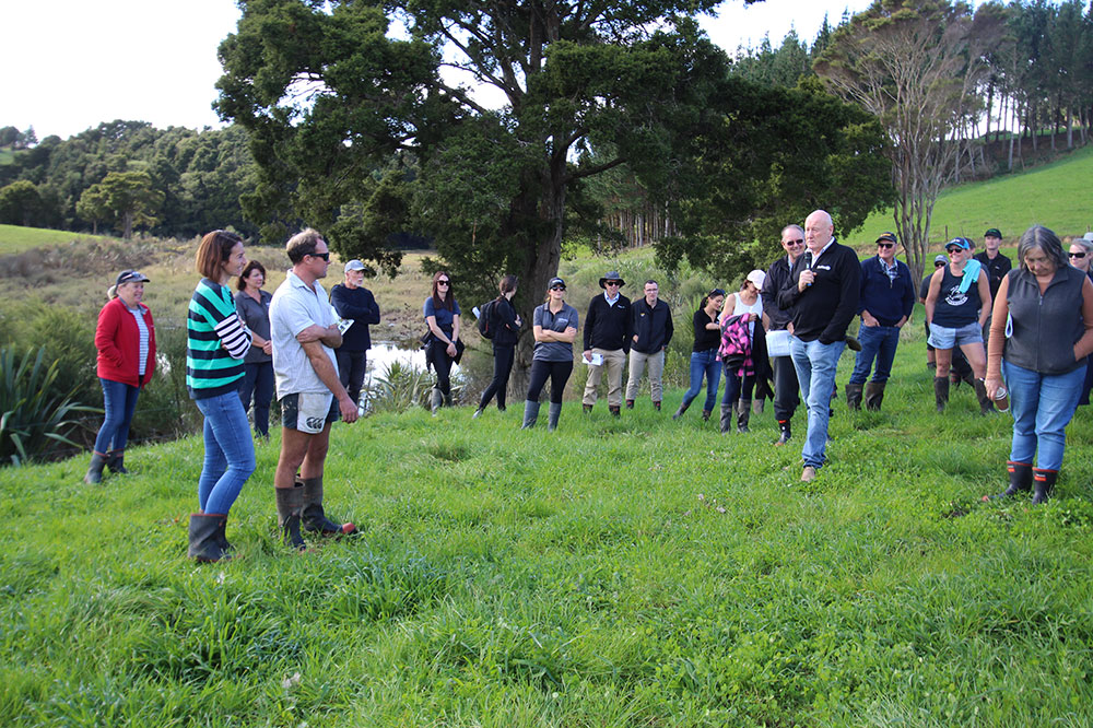 People on farm listening to person speaking.