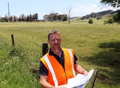 an wearing high viz standing in a paddock.