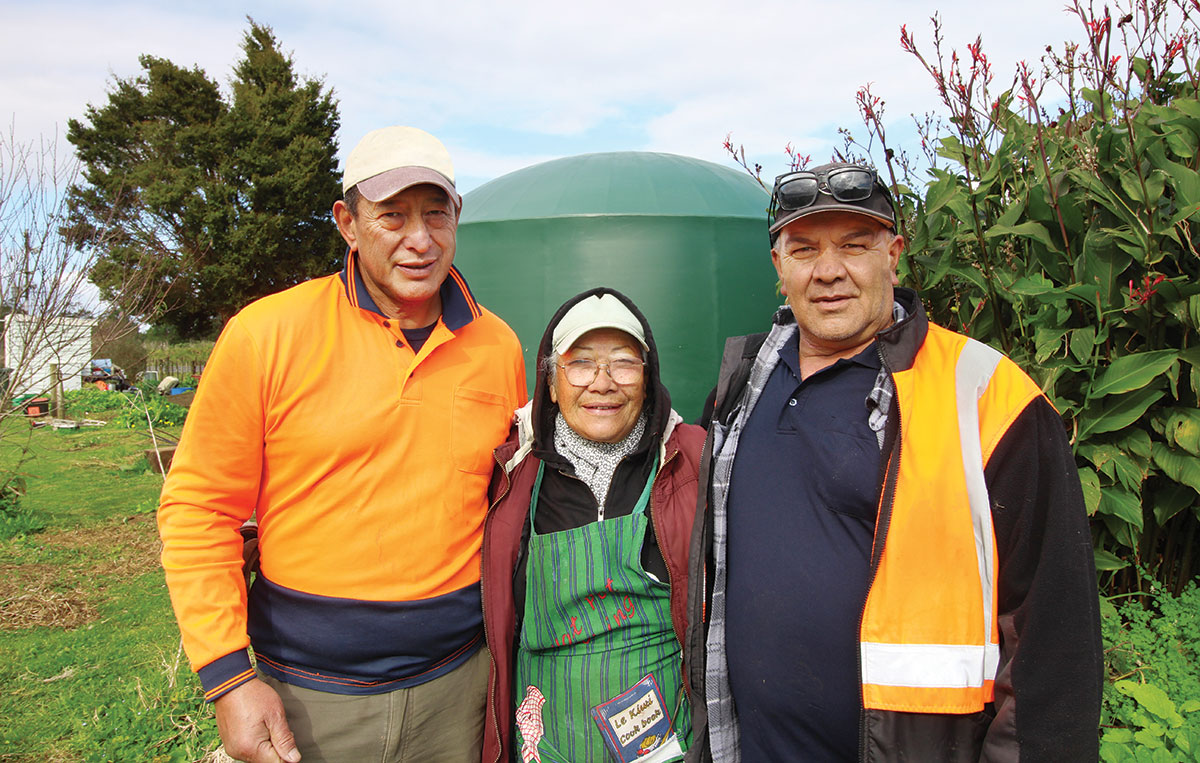 Two men and a woman standing in front of a water tank.