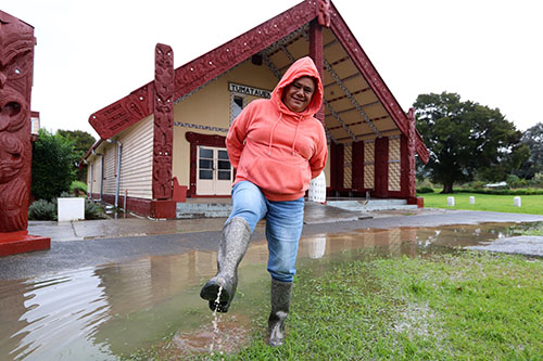 Woman in floodwater at marae.