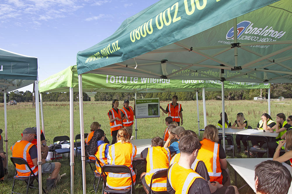 Students in hi-vis under a gazebo.