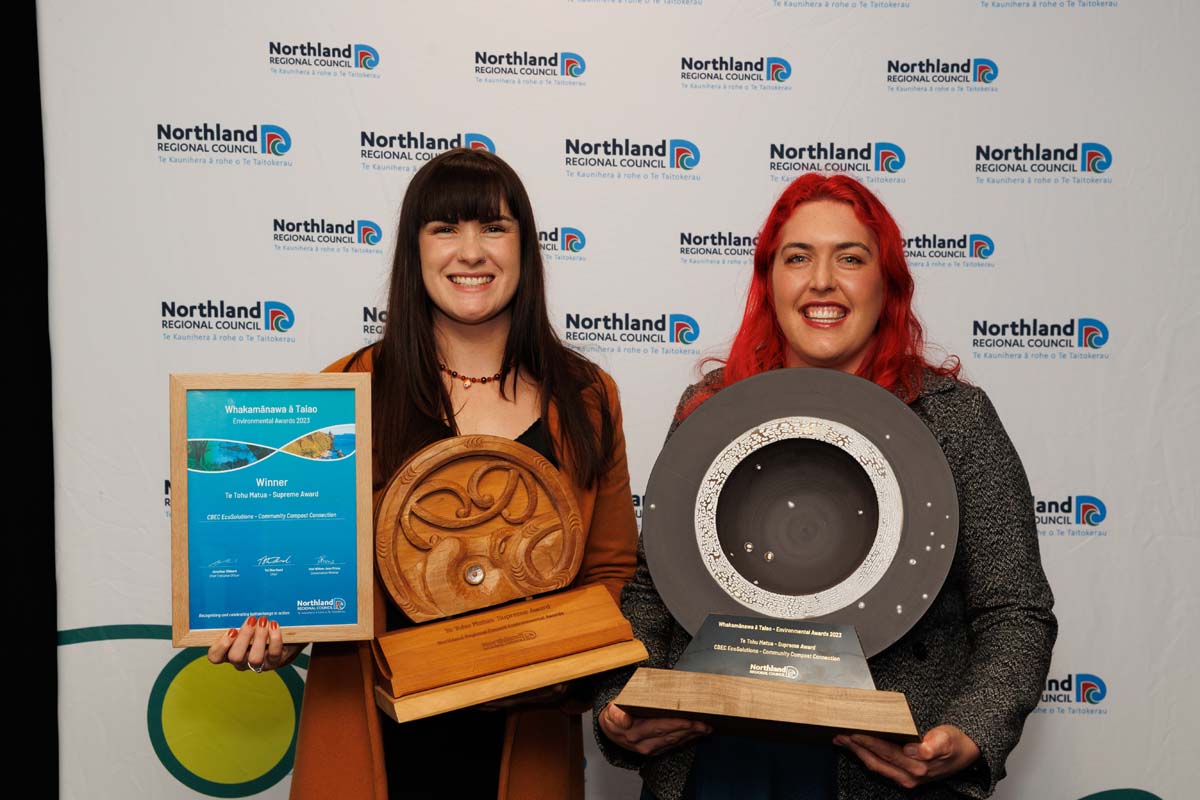 Two young women holding trophies and certificates.