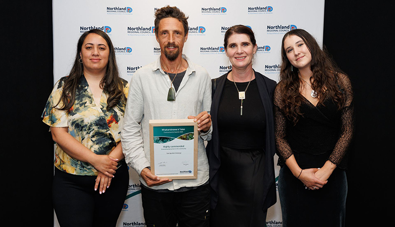Three women and one man holding a certificate in front of Northland Regional Council logo backdrop. (Photo: Dawn Dutton Photography).