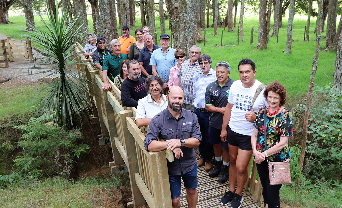 Group of people standing on bridge near trees.