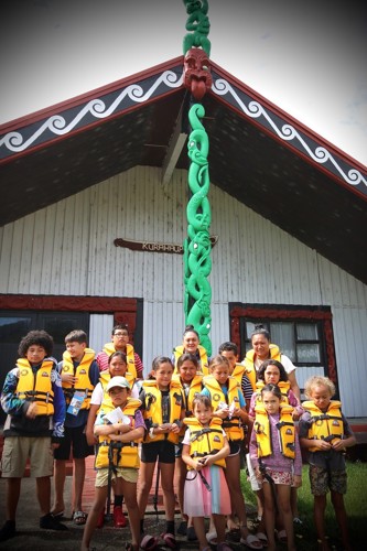 Children wearing lifejackets in front of marae.