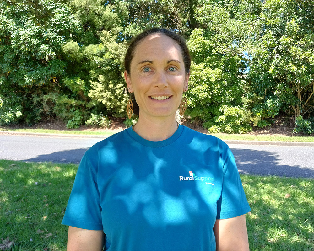 Close-up of a woman wearing a blue t-shirt with trees in the background.