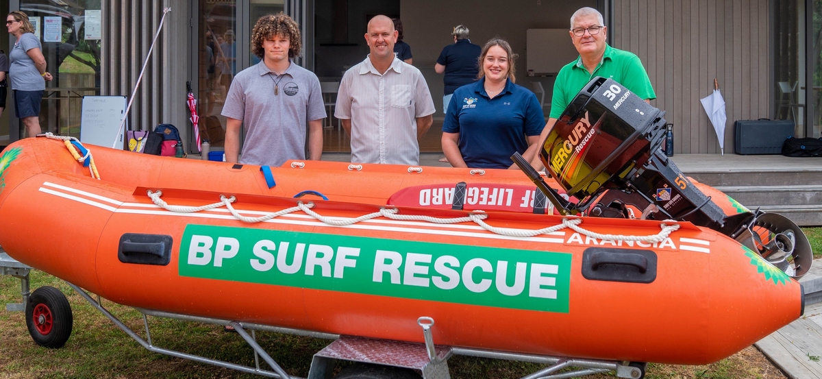 People standing behind surf rescue boat.