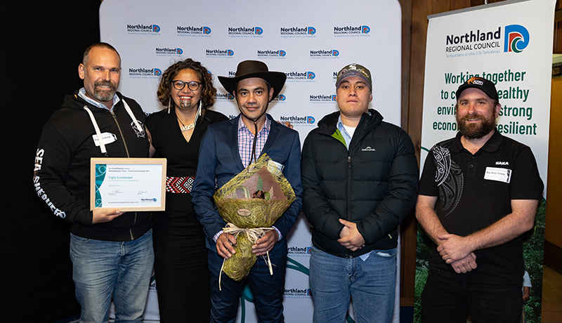 Group of people with flax flowers and certificate.