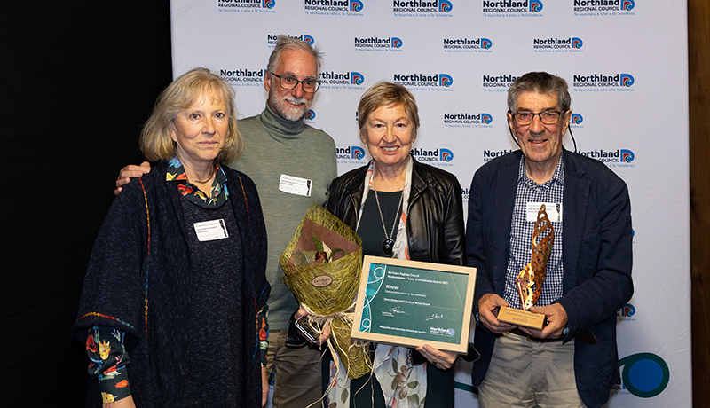 Four people with trophy and certificate.