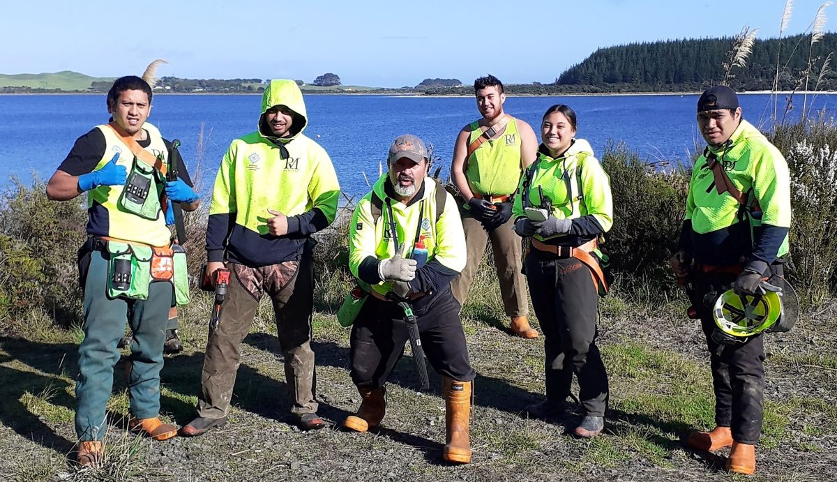 Team of people wearing safety gear in front of a lake.