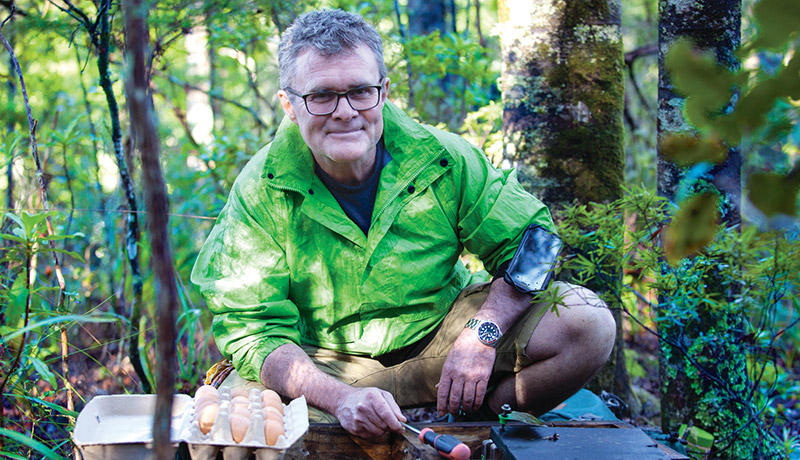 Man in bush setting pest traps.