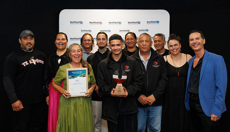 Group of men and women holding trophies and a certificate in front of Northland Regional Council logo backdrop. (Photo: Dawn Dutton Photography).
