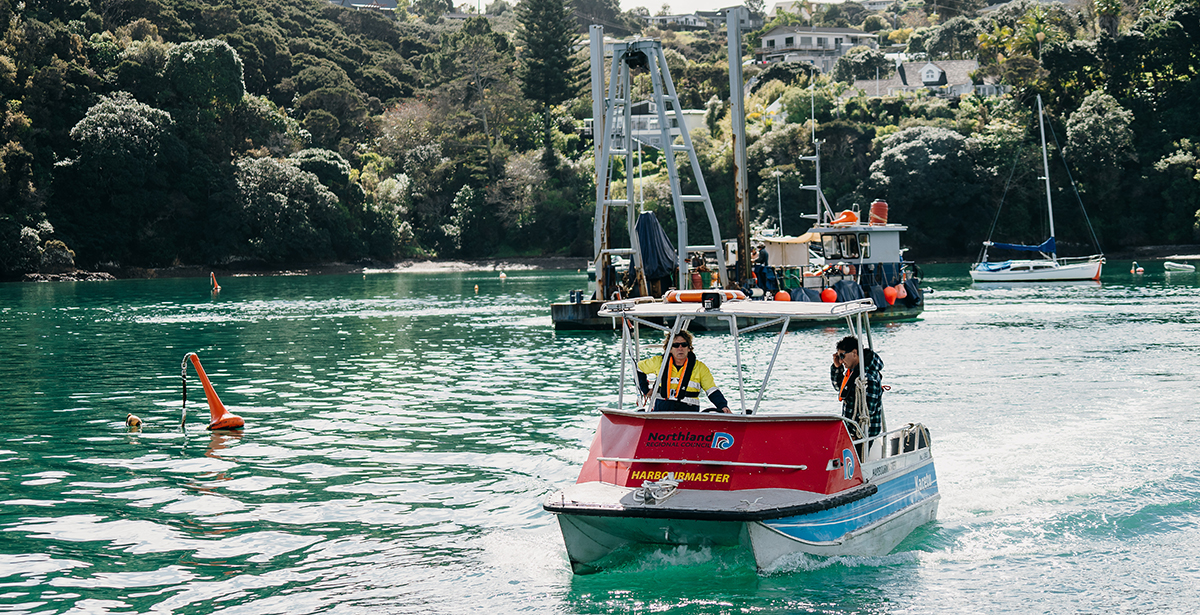 Small NRC vessel near mooring with moorings barge in the background.