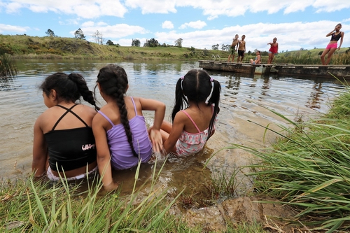 Children sitting in the water at Lake Waro.