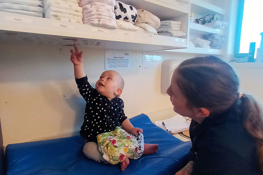 Baby Kylen ready for a cloth nappy change with mum and Kaiako Gabe.