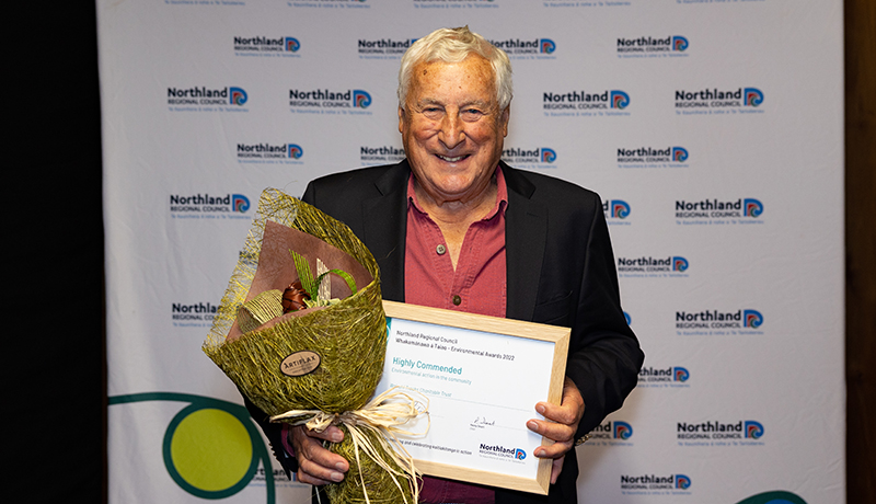 Man holding flax flowers and certificate.