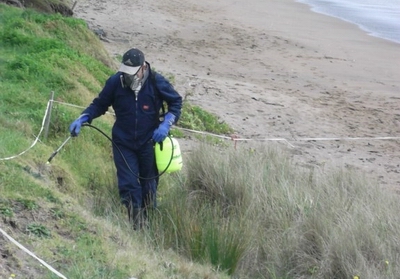 Person using protective clothing and equipment while spraying herbicide.